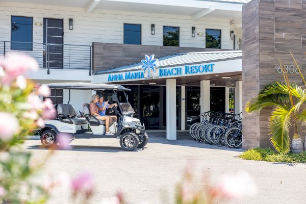 A couple sits in a golf cart in front of a building labeled 